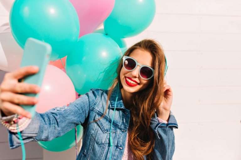 Junge Frau mit Luftballons fotografiert sich auf einem Event